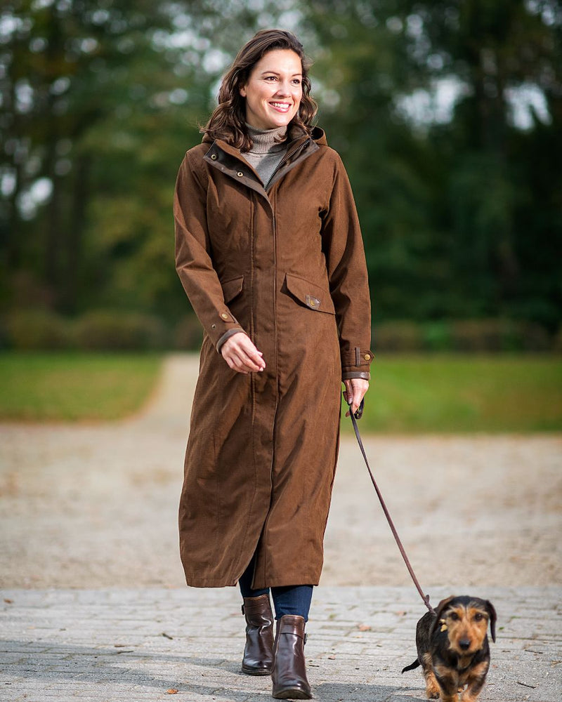 Earth Brown Coloured Baleno Kensington Long Waterproof Coat On A Countryside Background 