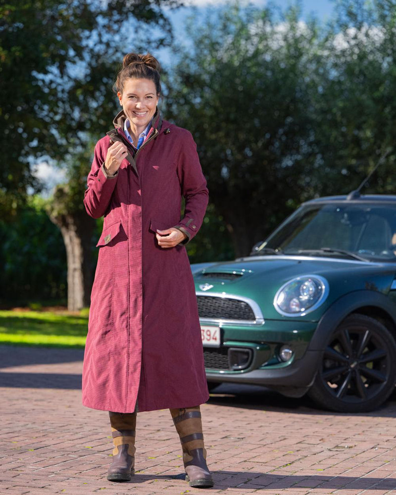 Raspberry Coloured Baleno Kensington Long Waterproof Coat On A Countryside Background 