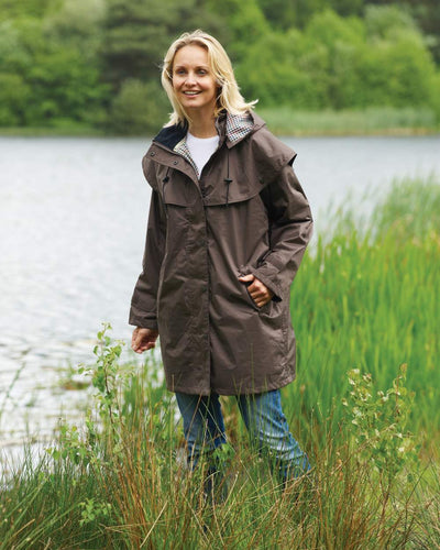 Brown coloured Champion Windsor Ladies' Three-Quarter Length Waterproof Coat on lake background #colour_brown