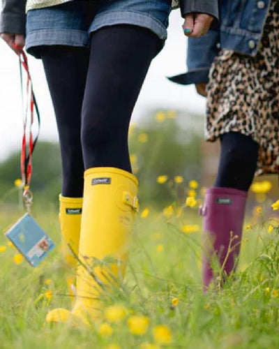 Yellow coloured Cotswold Sandringham Buckle Strap Wellingtons on grassy background #colour_yellow