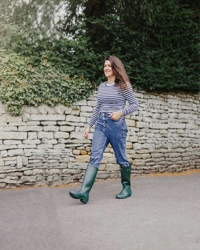 Green coloured Cotswold Windsor Buckle Strap Rubber Wellingtons on street background #colour_green