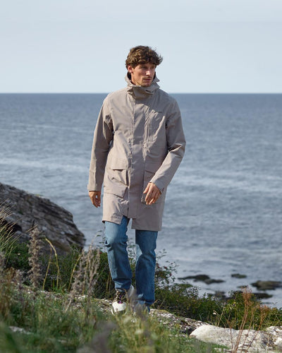 Ash Brown coloured Didriksons Andreas Unisex Parka 2 on coastal background #colour_ash-brown