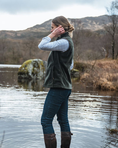 Pine Green Coloured Hoggs of Fife Stenton Ladies Fleece Gilet on lake background #colour_pine-green