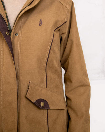 Camel coloured Jack Murphy Erin Long Waterproof Coat on wall background #colour_camel