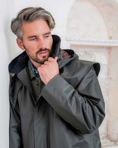 Olive coloured Jack Murphy Lambourne Mens Long Bush Coat on wall background #colour_olive