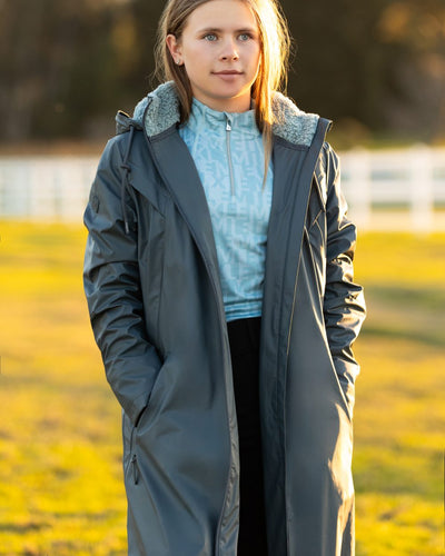 Petrol coloured LeMieux Young Rider All Elements Coat on blurry background #colour_petrol