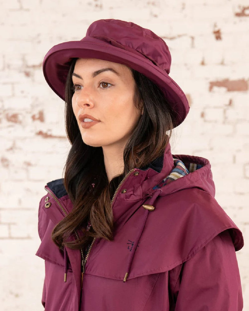 Plum coloured Lighthouse Canterbury Waterproof Hat on wall background 