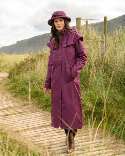 Plum coloured Lighthouse Outback Full Length Ladies Waterproof Raincoat on wood walk background #colour_plum