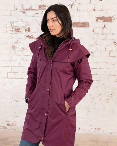 Plum coloured Lighthouse Outrider 3/4 Length Ladies Waterproof Raincoat on wall background #colour_plum