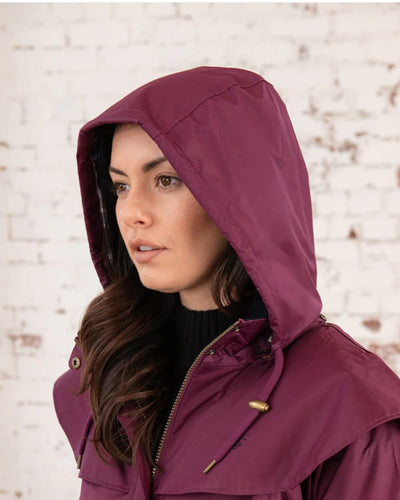 Plum coloured Lighthouse Outrider 3/4 Length Ladies Waterproof Raincoat on wall background #colour_plum