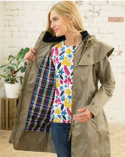 Fawn coloured Lighthouse Outrider 3/4 Length Ladies Waterproof Raincoat on wall background #colour_fawn