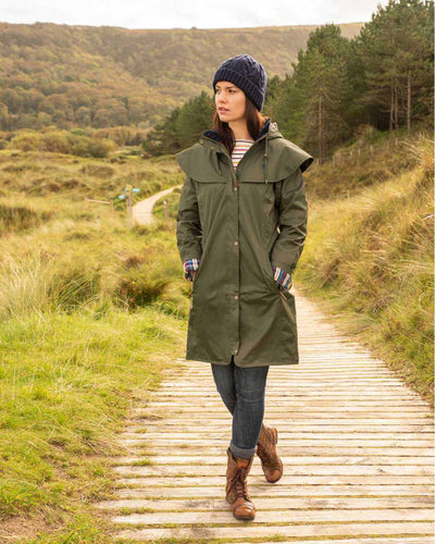 Fern coloured Lighthouse Outrider 3/4 Length Ladies Waterproof Raincoat on board walk background #colour_fern