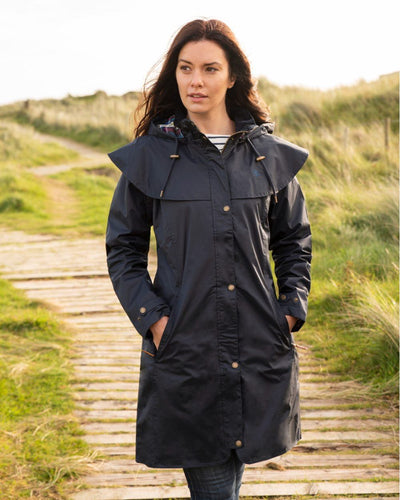 Nightshade coloured Lighthouse Outrider 3/4 Length Ladies Waterproof Raincoat on board walk background #colour_nightshade