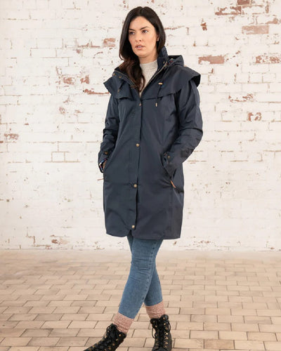 Nightshade coloured Lighthouse Outrider 3/4 Length Ladies Waterproof Raincoat on wall background #colour_nightshade