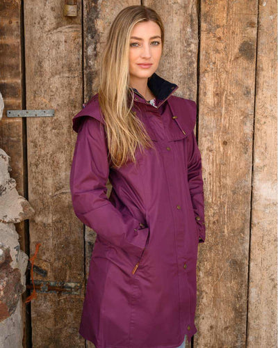 Plum coloured Lighthouse Outrider 3-4 Length Ladies Waterproof Raincoat - Clearance Colours on wooden door background #colour_plum