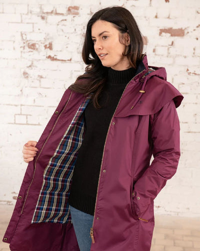 Plum coloured Lighthouse Outrider 3/4 Length Ladies Waterproof Raincoat on wall background #colour_plum