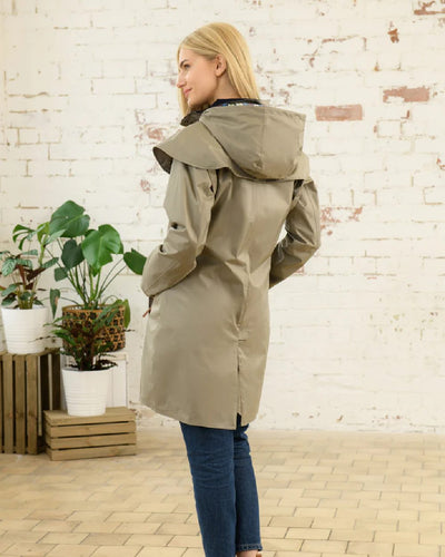 Fawn coloured Lighthouse Outrider 3/4 Length Ladies Waterproof Raincoat on wall background #colour_fawn