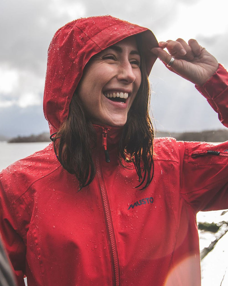 Red coloured Musto Ladies Sardinia Long Rain Jacket on sky background 