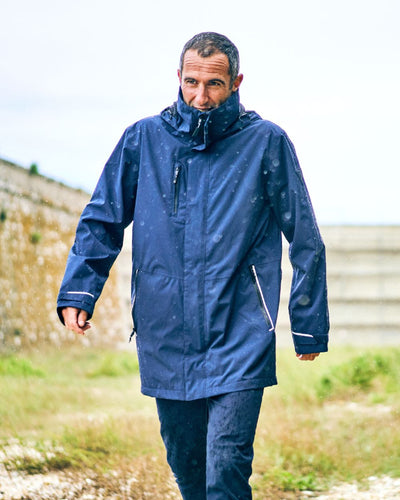 Navy coloured Musto Sardinia Long Rain Jacket on blurry background #colour_navy