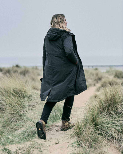 Black coloured Musto Womens Corsica Primaloft Longline Parka on grass background #colour_black