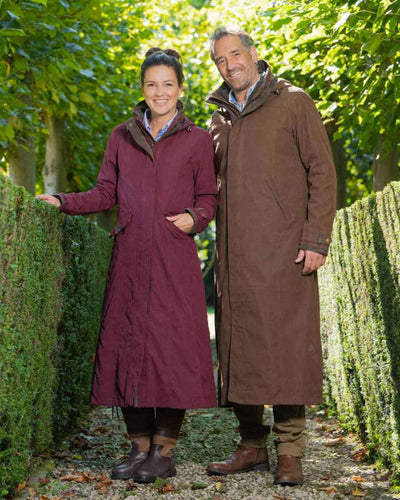 Earth Brown Coloured Baleno Livingstone Long Waterproof Coat On A Countryside Background #colour_earth-brown