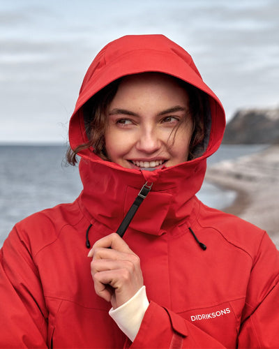 Pomme Red coloured Didriksons Womens Parka on beach background #colour_pomme-red