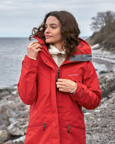 Pomme Red coloured Didriksons Womens Parka on beach background #colour_pomme-red