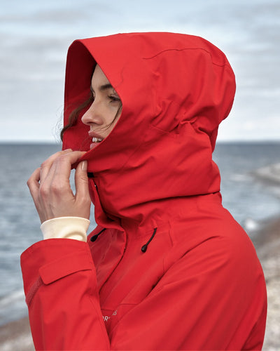 Pomme Red coloured Didriksons Womens Parka on beach background #colour_pomme-red