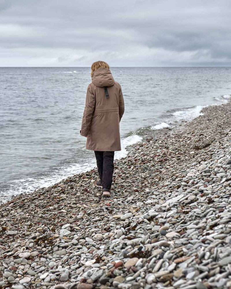 Mocha Brown Coloured Didriksons Womens Ilsa Parka On A Coastal Background 