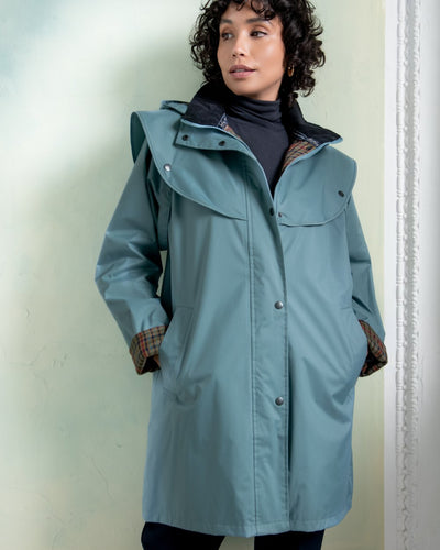 Smoke Blue coloured Jack Murphy Cotswold Ladies Waterproof 3/4 Coat on wall ocean background #colour_smoke-blue