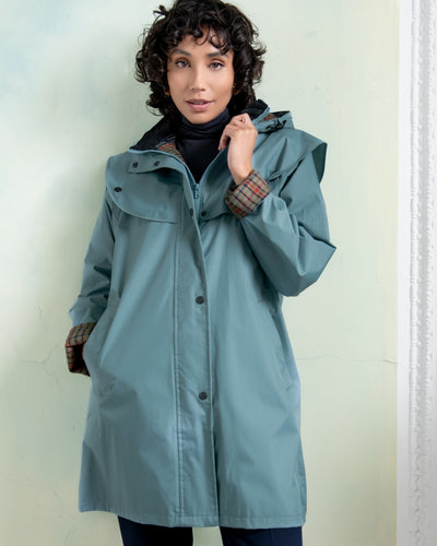 Smoke Blue coloured Jack Murphy Cotswold Ladies Waterproof 3/4 Coat on wall ocean background #colour_smoke-blue