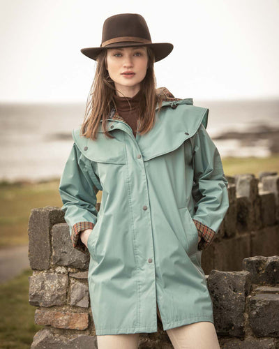 Smoke Blue coloured Jack Murphy Cotswold Ladies Waterproof 3/4 Coat on blurry ocean background #colour_smoke-blue